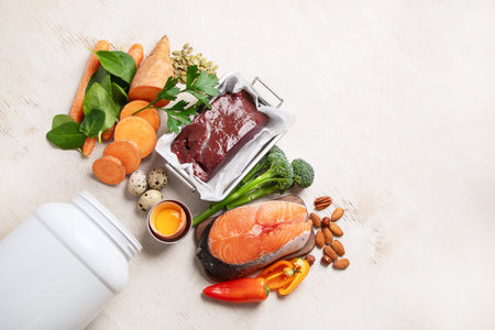 Vitamin A in food, natural products rich in vitamin A as red pepper, parsley leaves, dried apricots, carrots, broccoli, milk, egg yolk and cod liver oil on a light background. Top view.の写真素材