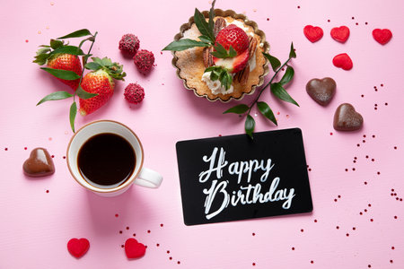 Festive pink background with cupcake, strawberries, chocolates, hot drink. Birthday celebration. Top viewの写真素材
