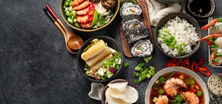 Traditional Asian food table. Spring roll, rice, shrimp, sushi, vegetables, meat on dark background. Top view, copy spaceの写真素材