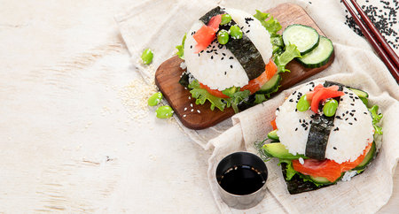Hybrid modern food. Sushi burger with salmon, white rice, avocado, cucumber. Copy spaceの写真素材