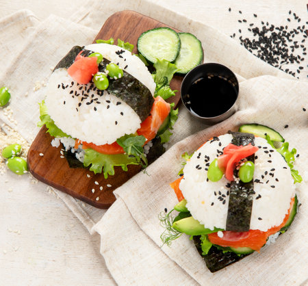 Hybrid modern food. Sushi burger with salmon, white rice, avocado, cucumber. Top viewの写真素材