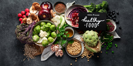 Vegan food. Pepper, broccoli, cabbage, garlic, mushrooms, pomegranate on a dark background. Top view, bannerの写真素材