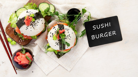 Hybrid modern food. Sushi burger with salmon, white rice, avocado, cucumber. Top viewの写真素材