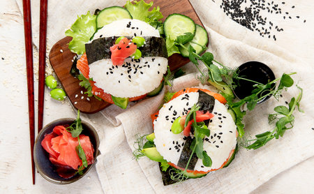 Hybrid modern food. Sushi burger with salmon, white rice, avocado, cucumber. Top viewの写真素材