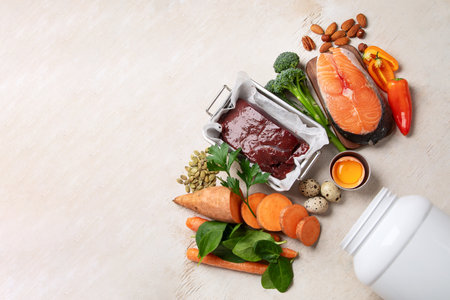 Vitamin A in food, natural products rich in vitamin A as red pepper, parsley leaves, dried apricots, carrots, broccoli, milk, egg yolk and cod liver oil on a light background. Top view. Copy space.の写真素材