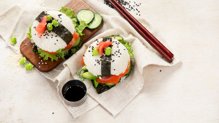 Hybrid modern food. Sushi burger with salmon, white rice, avocado, cucumber. Top view, copy spaceの写真素材