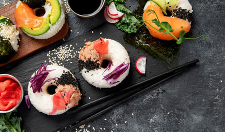 Sushi donuts on a dark background. Hybrid trend food. Top view, copy spaceの写真素材