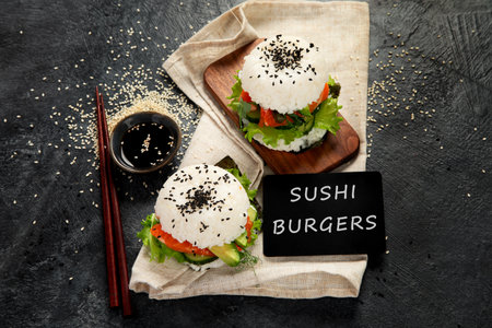 Asian sushi burger, soy sauce, chopstick on dark background. Trendy hybrid food.Top viewの写真素材