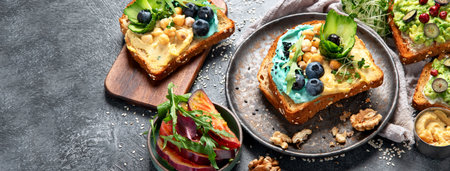 Vegetarian toasts with hummus, blueberry, avocado, tomato. delicious vegan breakfast on dark background. Top view, copy spaceの写真素材