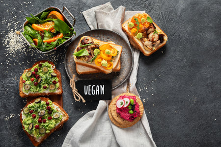 Vegan toast with avocado,mushroom and fresh salad on dark background. Vegetarian food concept. Top view, copy spaceの写真素材