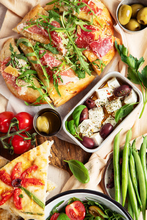 Full table of Italian meals on plates pizza, pasta, ravioli, salad and focaccia on white background. Top viewの写真素材