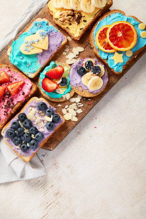 Sweet breakfast. Colorful toasts with fruits and berries. Children's food concept. Top view, copy spaceの写真素材