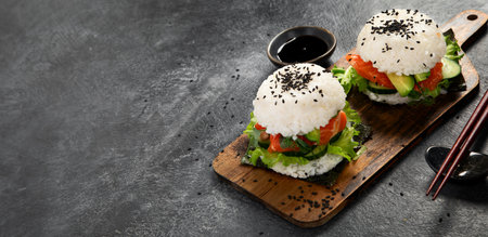 Asian sushi burger, soy sauce, chopstick on dark background. Trendy hybrid food. Copy space, bannerの写真素材