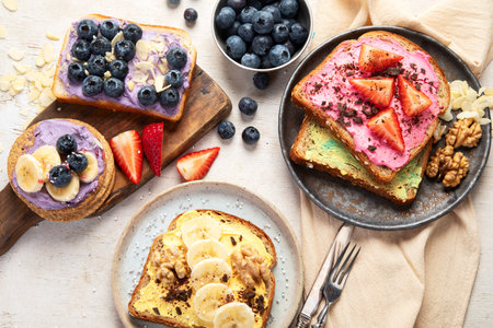 Sweet toast assortment. Banana, cream cheese, peanut butter and strawberry, cream cheese and blueberry on a white background. Top view.の写真素材
