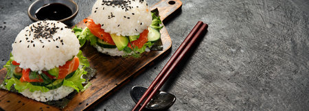 Asian sushi burger, soy sauce, chopstick on dark background. Trendy hybrid food. Copy space, bannerの写真素材