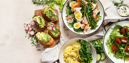 Spring fresh food with green leaf. Salads with strawberries, bacon and ravioli on light wooden background. Top view, copy space, bannerの写真素材