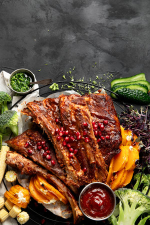 Pork ribs with vegetables on black background. Food for picnic concept. Top view, copy spaceの写真素材