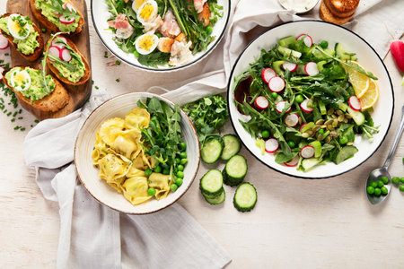 Spring fresh food with green leaf. Salads with strawberries, bacon and ravioli on light wooden background. Top viewの写真素材