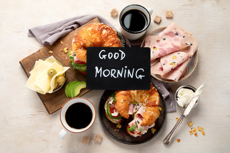 Fresh croissant sandwich with ham, cheese, avocado with coffee on white background, top view.の写真素材