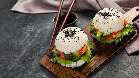 Asian sushi burger, soy sauce, chopstick on dark background. Trendy hybrid food. Copy spaceの写真素材