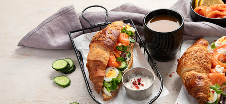 Croissant sandwich with cream cheese, cucumber, salmon and salad on a white background, top view. Healthy breakfast concept. Copy space.の写真素材
