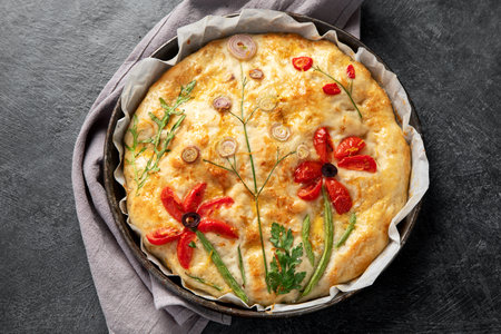 Floral painting focaccia, Italian garden flatbread art with tomatoes, onions and parsley on dark background. Top view.の写真素材
