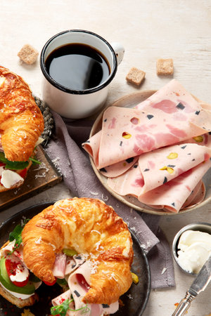 Fresh croissant sandwich with ham, cheese, avocado with coffee on white background, top view.の写真素材