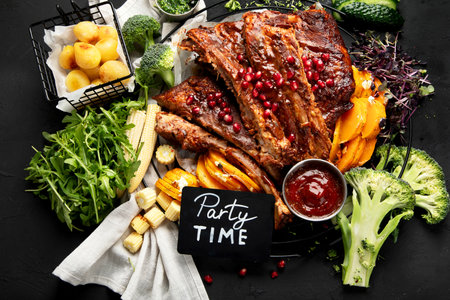 Pork ribs with vegetables on black background. Food for picnic concept. Top viewの写真素材