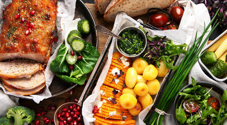 Roasted sliced ham with vegetables, bread and fresh salad on a black background. Top view.の写真素材