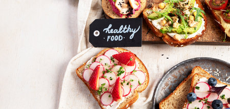 Various of vegan sandwiches on a light background. Healthy toasts with cheese, avocado, arugula, tomatoes and hummus. Healthy eating. Top view. Panorama with copy space.の写真素材