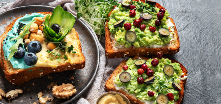 Vegetarian toasts with hummus, blueberry, avocado, tomato. delicious vegan breakfast on dark background. Copy spaceの写真素材