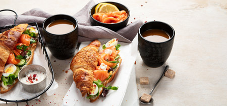 Croissant sandwich with cream cheese, cucumber, salmon and salad on a white background, top view. Healthy breakfast concept. Copy space.の写真素材