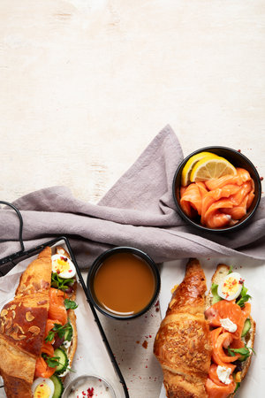 Croissant sandwich with cream cheese, cucumber, salmon and salad on a white background, top view. Healthy breakfast concept. Copy space.の写真素材