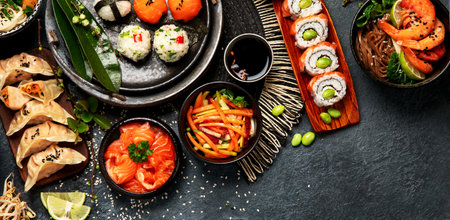 Sushi and Japanese food on a dark background. Sushi rolls, soup, fried rice, nigiri, soy sauce, chopsticks. Asian/Japanese food frame. Top view. Copy space.の写真素材