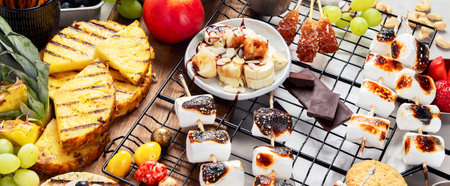 Assortment of grilled sweets and fruits. Summer bbq table. Pineapple, peach, banana, marshmallow, strawberry, blueberry on light background. Top viewの写真素材