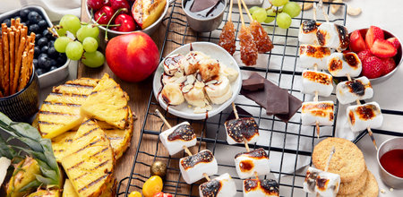 Assortment of grilled sweets and fruits. Summer bbq table. Pineapple, peach, banana, marshmallow, strawberry, blueberry on light background. Top view, bannerの写真素材