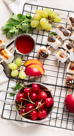 Marshmallow skewers and strawberry, cherry, grame on light wooden background. Summer party food. Top viewの写真素材