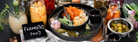 Fermented products on a dark background. Pickled vegetables in jars. Top view, bannerの写真素材