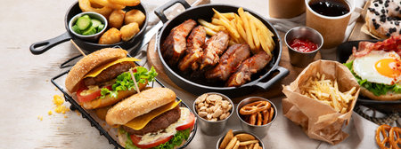 Various of american food, French fries, hamburgers, chips, popcorn, snacks and sauces on a white background, top view. Panorama with copy space.の写真素材