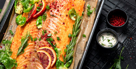 Cooked seafood on a black background. Baked salmon with onion, lemon, pomegranate juice. Top view