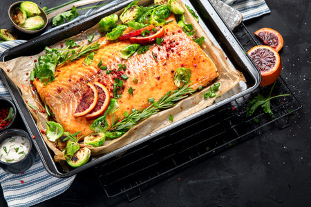 Cooked seafood on a black background. Baked salmon with onion, lemon, pomegranate juice. Top viewの写真素材