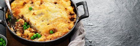 Shepherd's Pie with ground beef, potato and cheese on black background, top view. Traditional...