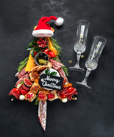 Christmas tree from cheese and meat appetizers on a dark background. Winter holidays snack. Top view.の写真素材