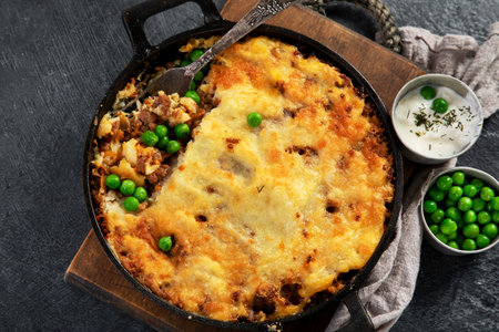 Shepherd's Pie with ground beef, potato and cheese on black background, top view. Traditional homemade potato casserole with green pea.の写真素材