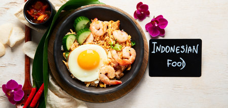 A plate of Nasi Goreng with rice, vegetables, and an egg on top on a light background. Top view. Panorama.の写真素材