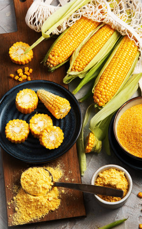 Corncobs and corn groats on gray background. Harvest food concept. Top view, flat lay, copy spaceの写真素材