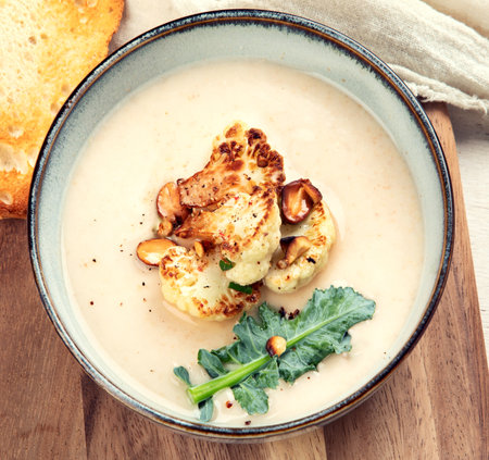 Creamy cauliflower soup with nuts and herbs. Top view.の写真素材