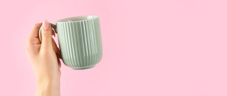 Arms raised up holding coffee cup on pink background.の写真素材