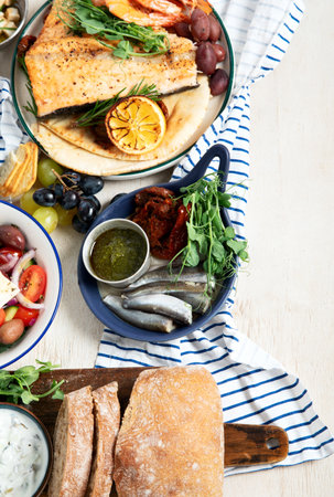 Greek food background. Fsh, pita, Greek salad, tzatziki, feta, olives. Traditional different Greek dishes set on a light background. Top view. Copy space.の写真素材