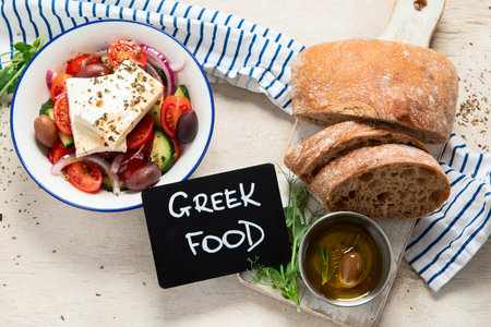 Fresh vegetable healthy Mediterranean food salad of Greek feta cheese, onion, tomato, olives, cucumber and bread on board. Top view, light background.の写真素材
